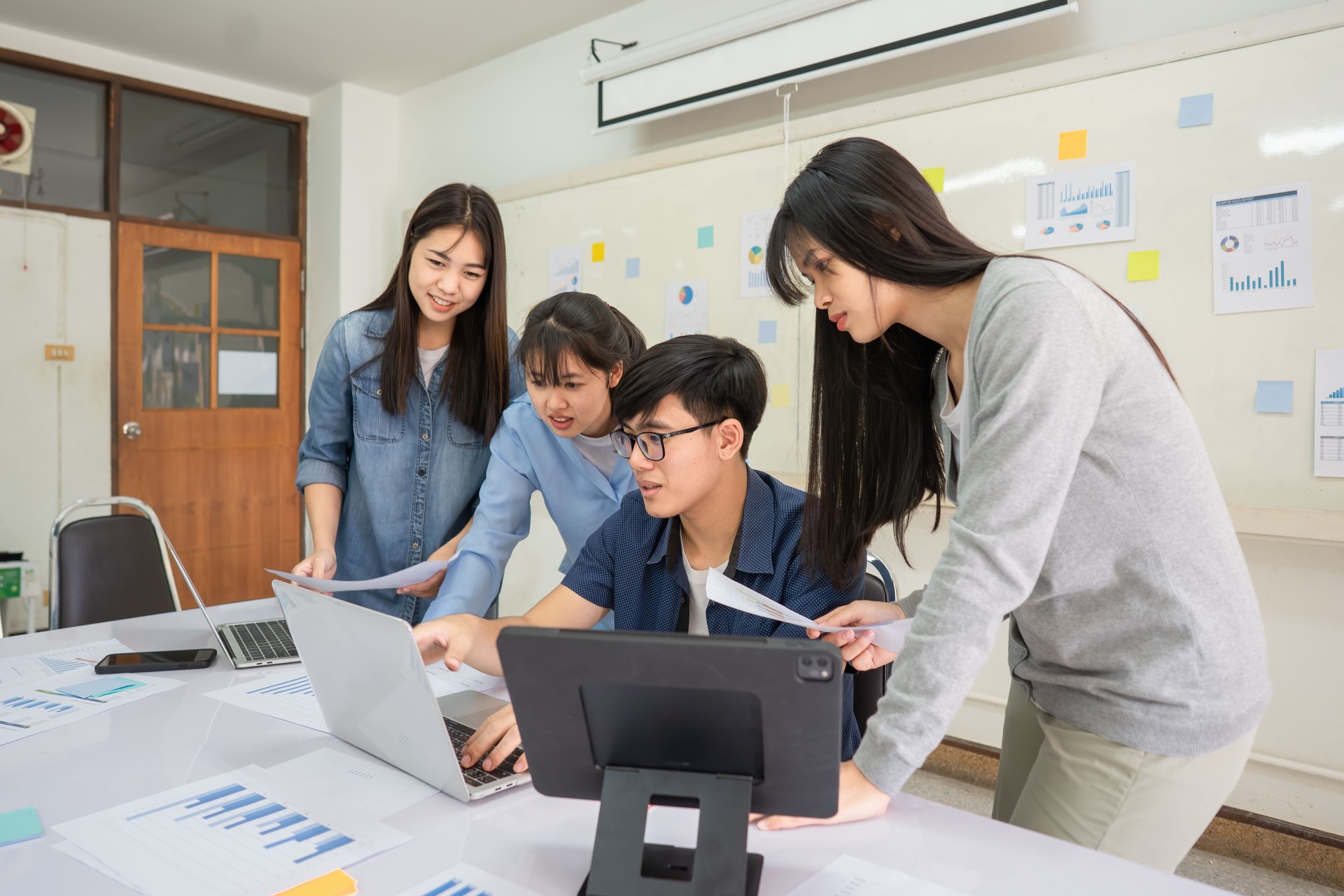 college students discussing project on laptop in classroom